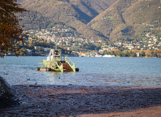 Fototapeta na wymiar sweeping boat to remove an expanse of debris brought by the rain.Como lake, italian lakes, Lombardy, Italy