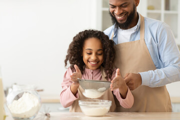 Cheerful black man and his daughter preparing dough