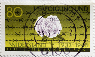 GERMANY - CIRCA 1983 : a postage stamp from Germany, showing the white rose in front of barbed wire...
