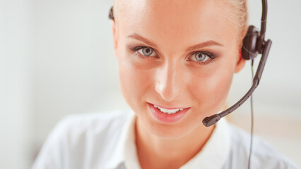 Portrait of pretty young female operator sitting at office desk with headset