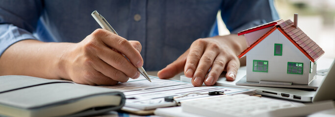 Close up house model with business man signs a purchase contract or mortgage for a home, Real...