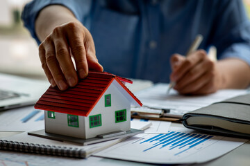 Close up house model with business man signs a purchase contract or mortgage for a home, Real estate concept.	