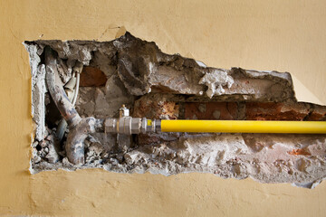 Baustelle mit neuer Rohrleitung in Mauer. 
Aufgestemmte Mauer. Trockenbau.
Construction site with new pipeline in brick wall. 
Pry open wall. Drywall.