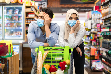 Unhappy Muslim Family Couple Struggling Crisis Buying Food In Supermarket