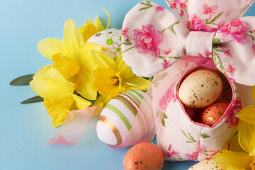 Colored Easter eggs in decorative basket and a bouquet of yellow narcissus