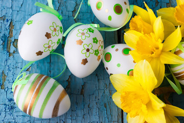 Colored decorative Easter eggs and a bouquet of yellow narcissus