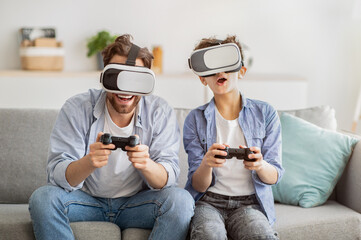 Virtual reality. Excited father and teen son trying VR glasses and playing videogames together