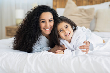 Adorable young mother and cute daughter bonding on bed