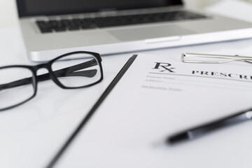 Rx prescription, laptop and glasses on pharmacy work table.