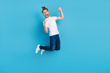 Full length portrait of delighted man fists up open mouth celebrate success isolated on blue color...