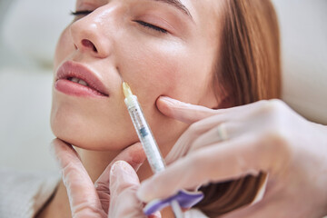 Charming young Caucasian female getting beauty injection in spa clinic