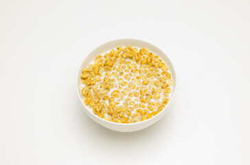 wheat flakes with milk in a white cup on a white background