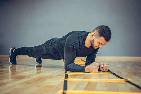 Fitness training athletic sporty man doing plank exercise in gym or home concept. Bearded man exercising workout aerobic at grey background.