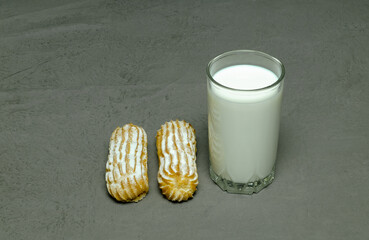clear glass with milk and two brewed cakes on a gray background