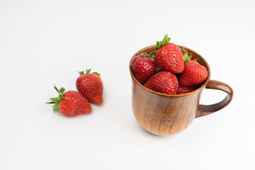 Strawberries in a wooden mug, on a light background. Summer concept, harvest, there is a place for text