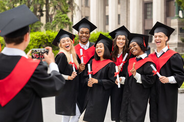 Positive international students celebrating graduation, taking photos