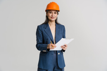 Asian smiling woman wearing helmet posing with clipboard and pencil