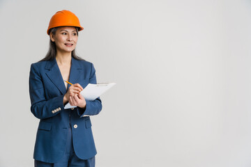 Asian smiling woman wearing helmet writing down notes