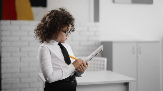 Thoughtful creative girl taking notes in paper notebook and smiling inspired happy