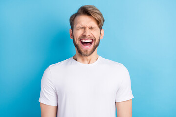 Photo portrait of young man in casual t-shirt laughing with opened mouth isolated bright blue color...