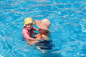 Mother and daughter bonding through play while spending time together in swimming pool on summer break.