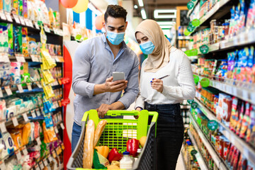 Muslim Family Using Smartphone Buying Food Groceries In Modern Supermarket