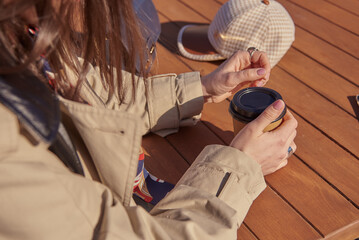 Obraz premium A woman in a street cafe with a cardboard cup in her hands.