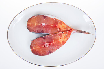 Fresh pangasius cut into pieces on a white plate.