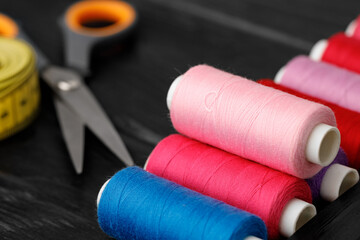 Colorful sewing utensils on black wooden surface