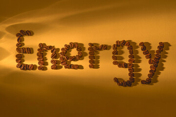 The inscription energy from coffee beans on an orange background in the rays of light refracted through a glass of water