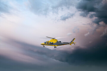 Fototapeta na wymiar Air Ambulance helicopter yellow medical emergency chopper taking off at dusk amazing dramatic storm sky as respond to 999 incident medic team