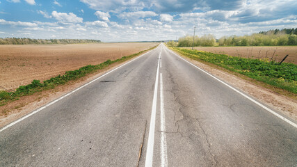 Endless country road to the horizon under cloudy sky