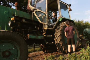 The boys are playing and looking at a large farm tractor. © Valentinka