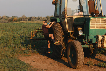 The boys are playing and looking at a large farm tractor.