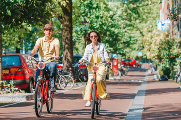 Young happy caucasian couple on bikes in old streets in Amsterdam - 429018540