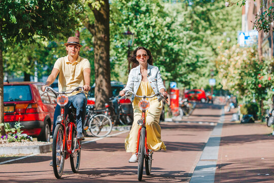 Young happy caucasian couple on bikes in old streets in Amsterdam