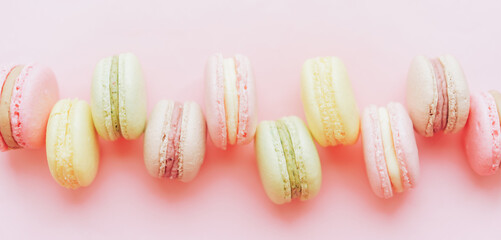 Background of Macaroons of different colors lie in a row against a pink background. A gift for a loved one. Delicious dessert for any occasion