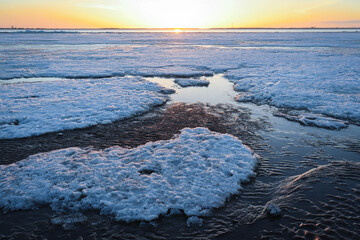 Ice on the frozen river. Scenic sunset icy landscape view.