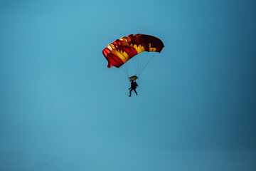 a skydiver descends to the ground from the sky in clear weather. extreme sports to overcome the fear of heights. free fall ends successfully