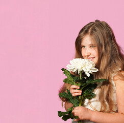  Portrait of happy smiling child girl with white flower on pastel pink background in the studio. Copy space. Happy Mother's Day greeting card.