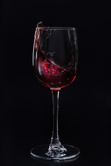 Glass with splashes of red wine isolated on a dark background