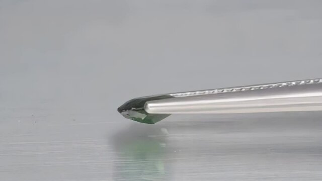 natural green chrome tourmaline in the tweezers on the turn table