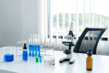science, laboratory tools set on the white table. microscope, tubes in the rack and blue liquid speciment