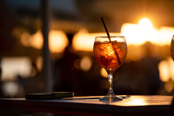 A golden cocktail drink on the table outside on sunset at the lake
