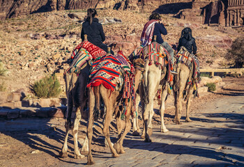 Tourists riding camels in Petra historic and archaeological city, Jordan
