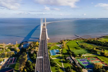 Photo sur Plexiglas Pont Vasco da Gama Aerial view of Vasco da Gama suspended bridge crossing the Tagus River during a beautiful sunny day, view of the highway deploying on the water, Lisbon, Portugal.