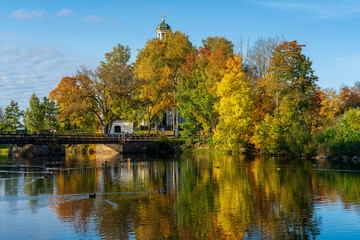Church tower by a river surrounded by vibrant autumn colored trees