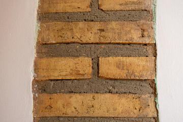 Detail of some bricks with mortar, in a white wall.
