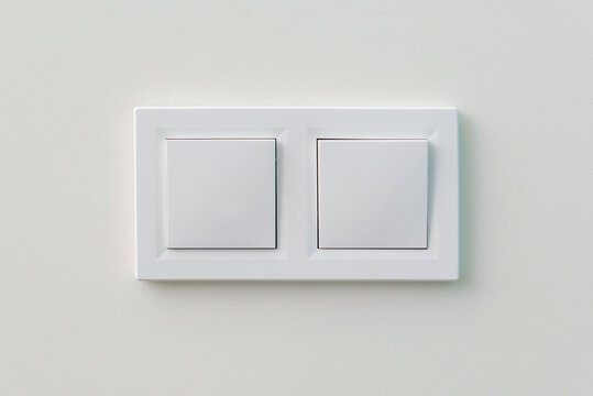 White light switch on the wall. Turn on or turn off the lights. Wall-mounted white double light switch.