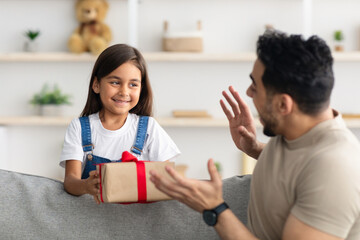 Little girl celebrating father's day, greeting excited dad with box